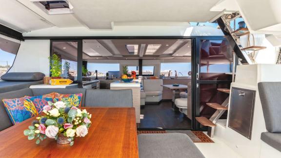 View of a stylishly decorated dining area and interior of a catamaran with an open sliding door.