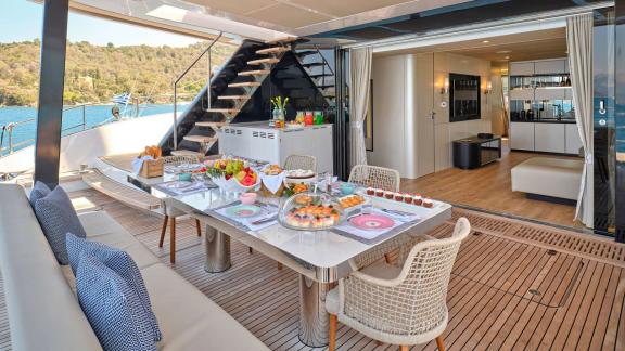 Stylishly set outdoor dining table on the Genny catamaran, with access to the luxurious interior.