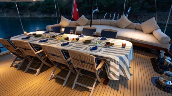 Elegantly set dining table on the deck of Yacht Kanarya at dusk.