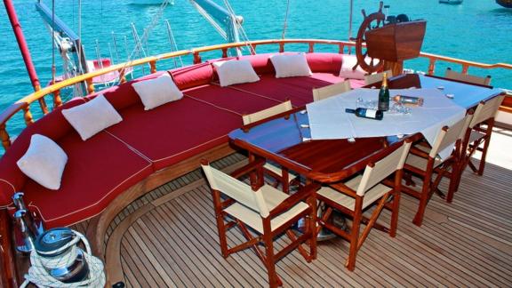 Set table and red cushioned benches on the aft deck of Gulet Il Fratello with sea view.