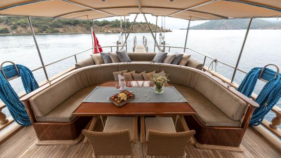 Luxurious seating area on Gulet Ceylan with a dining table, fruit platter, and sea view in Fethiye.