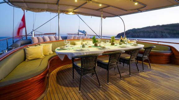 A beautifully laid dining table on the deck of the gulet La Bella Vita in Bodrum, with cosy lighting and a magnificent s