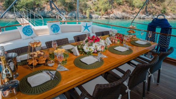 A beautifully set table on the Gulet Cemre Mila with a view of turquoise water and the coast.