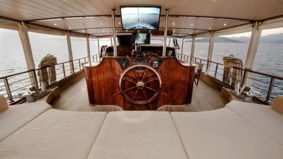 Steering wheel and the steering console of a yacht with a large screen above it.