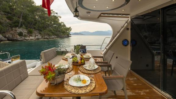 Essbereich auf dem Achterdeck der Motoryacht Golden Blue, vor Anker in einer malerischen Bucht.