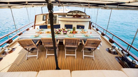 A beautifully set dining table on the deck of Yacht Kanarya with a sea view.