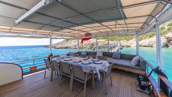 Elegant dining area under a shaded canopy with views of the sea and coastline.