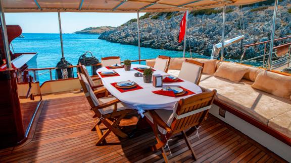 Elegant dining area on the 24-meter Gulet Sani Kaptan 2 with sea view, perfect for outdoor meals in Bodrum, Turkey.