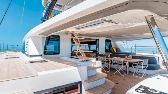 Open flybridge with stairs, seating, and dining table on the catamaran Amada Mia