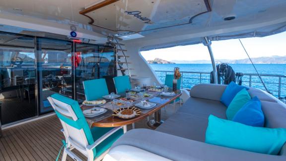 Dining area with a set table on the outdoor deck of Gulet Destiny, overlooking the sea.