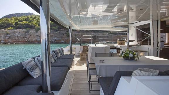 The spacious outdoor area of the Lagoon 560 in Athens, featuring comfortable seating and an elegant dining table, offers