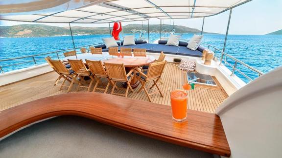 The cosy dining area on the deck of the Gulet Bella Mare in Bodrum, with wooden furniture, comfortable loungers and a ma