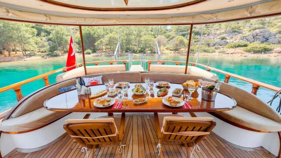 Stilvoll gedeckter Tisch im Essbereich der Gulet Blu Dream mit Blick auf türkisfarbenes Wasser.