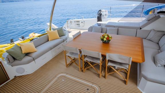 Outdoor area with dining table and sofas, overlooking the sea and water sports equipment.