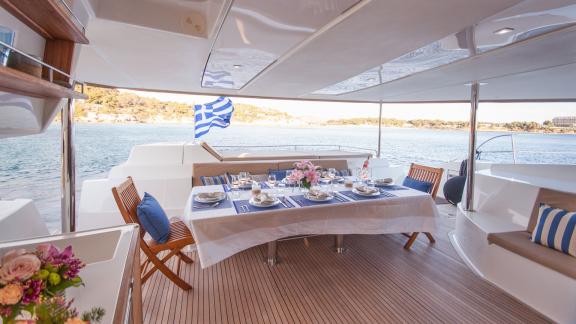 The aft deck of catamaran High Five features an elegant dining table with sea views.