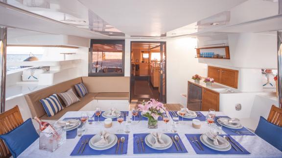 The aft deck of catamaran High Five features an elegant dining table and a comfortable seating area.