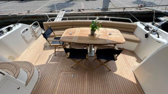 The spacious aft deck of the Distraction motor yacht is equipped with an elegant dining table and a comfortable seating 