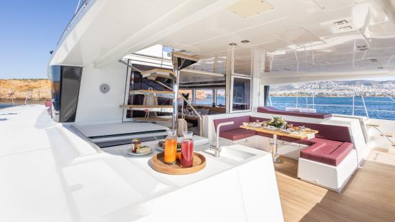 Open lounge with refreshments and a set dining table on the Lagoon 560 catamaran King of Diamonds.