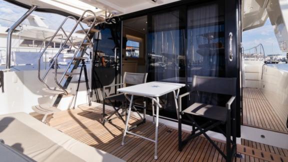 The aft deck of the motor yacht Ocean Dreamer in the harbor features a comfortable seating area with a small table and c