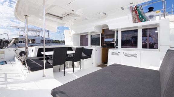 The cozy seating and dining area at the stern of the Saelma Lagoon 450 with table and cushioned benches.