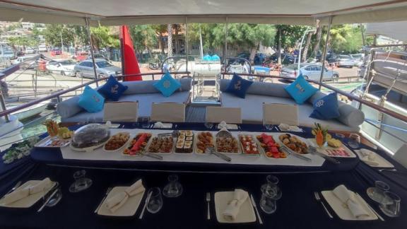 Set dining table with appetizers and a cozy seating area on the deck of a yacht.