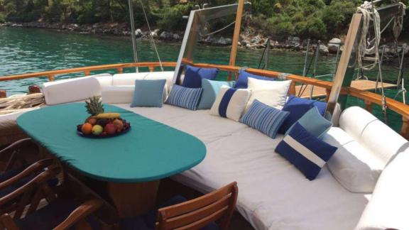 Inviting seating area on Gulet Miramare with cushions and a set table, perfect for socializing on board.