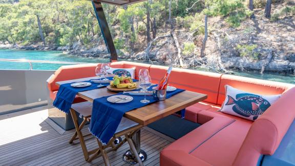 Cozy dining area on the deck of the Gottiri motor yacht with fruits and wine.