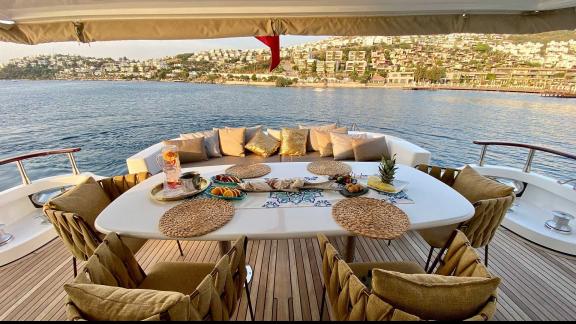 The aft deck of Vedo B yacht features an elegant dining table and comfortable seating area with a sea view.