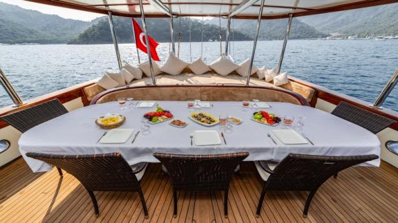 The dining table on the deck of the gulet yacht Amazon Solo, set and ready for a meal with a view of the sea.