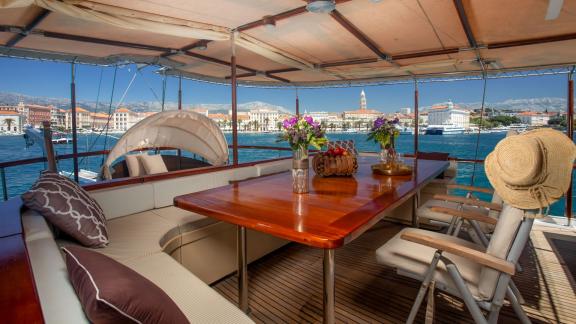 Cosy dining area on a gulet with a view of a picturesque Croatian harbour town.