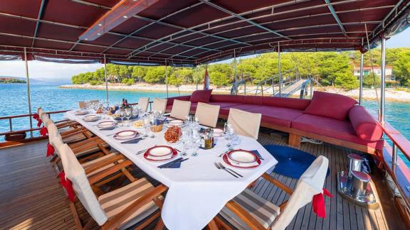 The aft deck of gulet Croatia features an elegantly set long dining table and a spacious seating area.