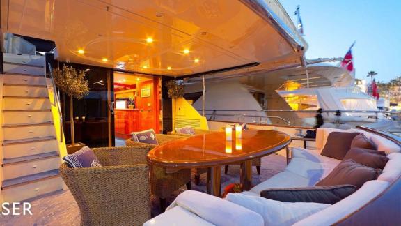 The aft deck of motor yacht Riva 21 features a cozy seating area and a stylish dining table.