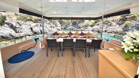 The aft deck of the trawler Compass features a comfortable seating area and a large dining table.