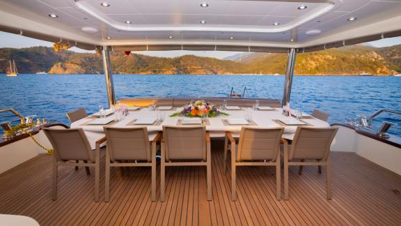 The outdoor dining area on the aft deck of the luxury trawler Lycian Dream in Fethiye features a large table with a sea