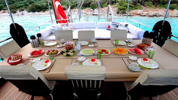 Lavishly set breakfast table on the deck of Gulet Ali Aga 1 overlooking turquoise waters.