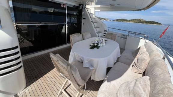 The aft deck area of the yacht Cielo features comfortable seating and a round dining table with a sea view.