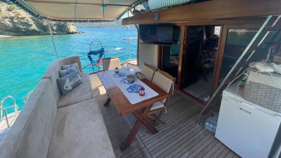 The aft deck seating and dining area of motor yacht Grida is equipped with comfortable chairs and a table.