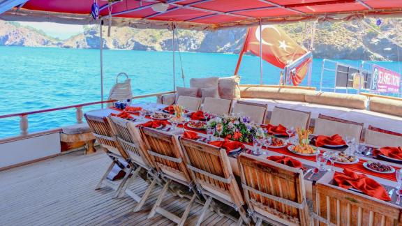 The aft deck of gulet Sea Angel 2 features an elegantly set long dining table with a view of the sea.