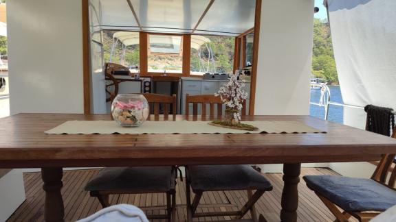 Dining area on Gulet Nostalji with wooden table, chairs, and view of the water in Göcek.