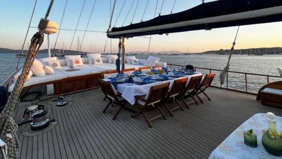 The aft deck of gulet Barka features a beautifully set dining table with a view of the sea.