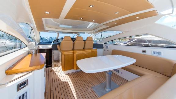 The deck of Aron 26 motor yacht includes a cozy seating area, table and helm station.