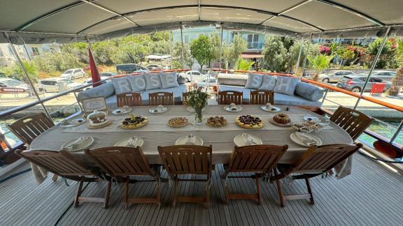 The aft deck of gulet Rose Sah features a large dining table beautifully set.