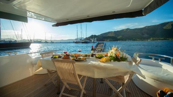 Der Essbereich auf dem Achterdeck der Motoryacht My Spica bietet ein luxuriöses Abendessen mit Meerblick.