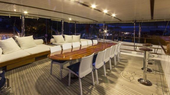 The aft deck of Gulet Cemre 4 features a large dining table and comfortable seating area.