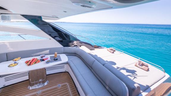 The aft deck of motor yacht Make My Day features a comfortable seating area and stunning sea views.