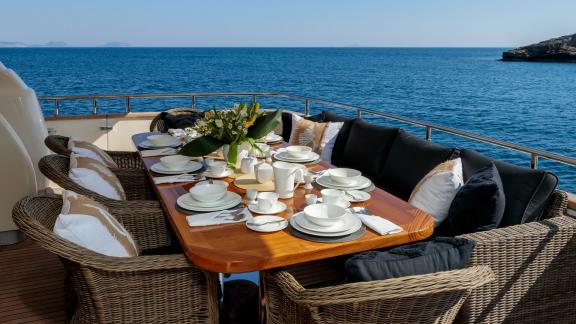 The outdoor dining area on yacht Miraval features an elegant table setting with a sea view.