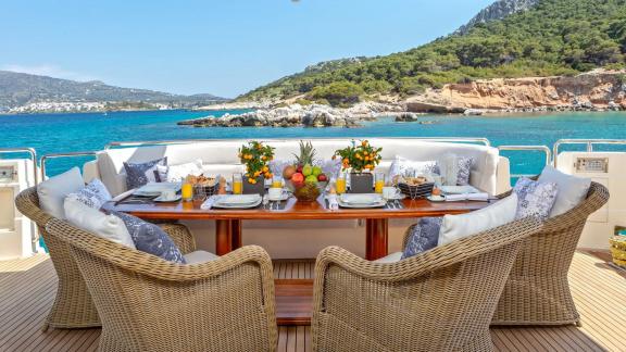 Elegant table, chairs, and scenic view on Divine's aft deck.