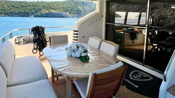 Freya motoryatının arka güvertesindeki bu masa, Bodrum koylarında sakin bir öğle yemeği için şık ve huzurlu bir ortam su