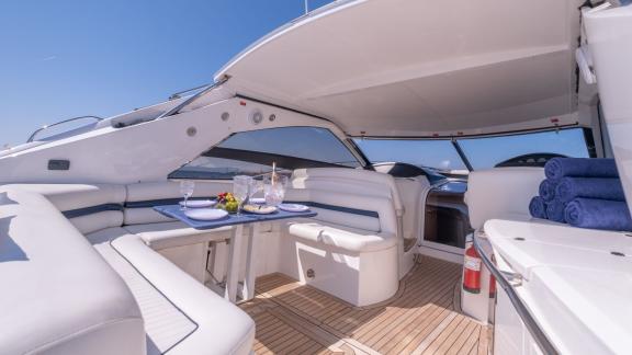 Ibiza açıklarında demirlemiş Stress motoryatın gölgeli kokpit kısmında masa ve oturma alanı bulunuyor.