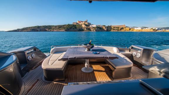 Die Yacht Optimum bietet im Heckbereich eine Sitzgruppe mit Tisch. Dahinter liegt die historische Altstadt von Ibiza.